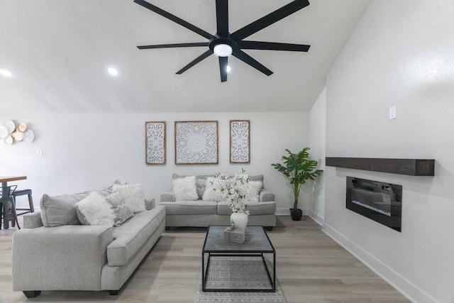 3618 Tamfield Dr, Houston, TX 77066 - living room featuring lofted ceiling, a ceiling fan, a glass covered fireplace, recessed lighting, and light wood finished floors