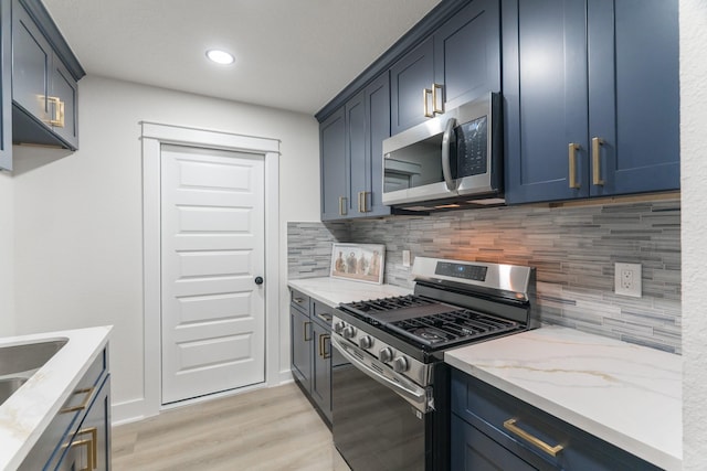 3618 Tamfield Dr, Houston, TX 77066 - kitchen featuring appliances with stainless steel finishes, blue cabinetry, light stone counters, tasteful backsplash, and recessed lighting