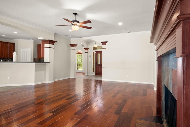 10 Hollow Glen Ln, Tomball, TX 77375 - unfurnished living room featuring a tile fireplace, ceiling fan, decorative columns, dark wood-style flooring, and recessed lighting