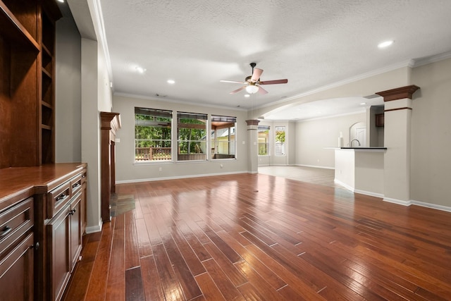 10 Hollow Glen Ln, Tomball, TX 77375 - unfurnished living room featuring ornate columns, a ceiling fan, crown molding, dark wood-style flooring, and baseboards