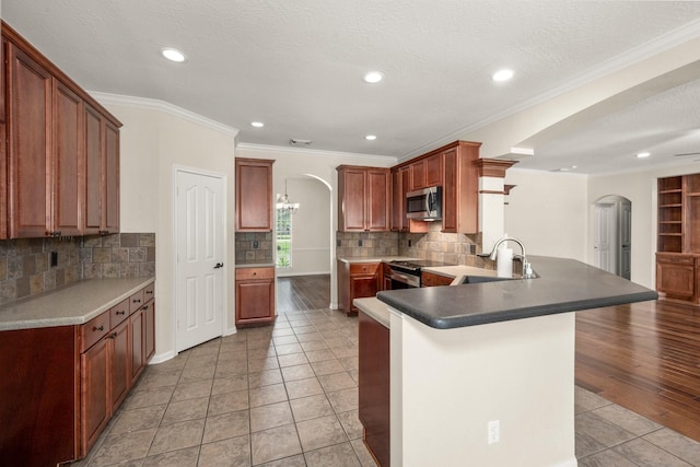 10 Hollow Glen Ln, Tomball, TX 77375 - kitchen featuring arched walkways, stainless steel appliances, a sink, a peninsula, and light tile patterned flooring