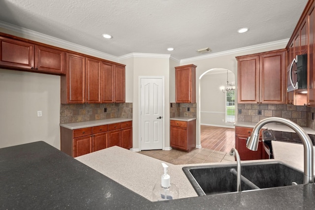 10 Hollow Glen Ln, Tomball, TX 77375 - kitchen featuring arched walkways, a sink, stainless steel microwave, decorative backsplash, and recessed lighting