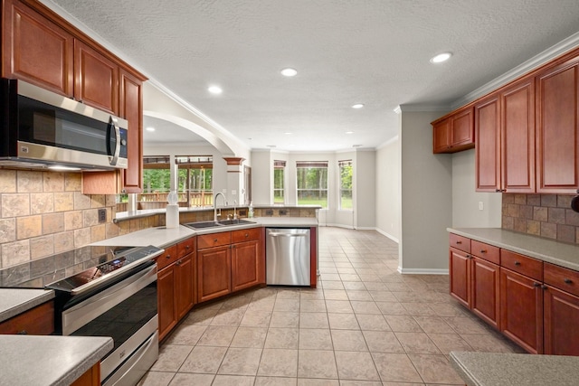 10 Hollow Glen Ln, Tomball, TX 77375 - kitchen with appliances with stainless steel finishes, a sink, a peninsula, backsplash, and ornamental molding