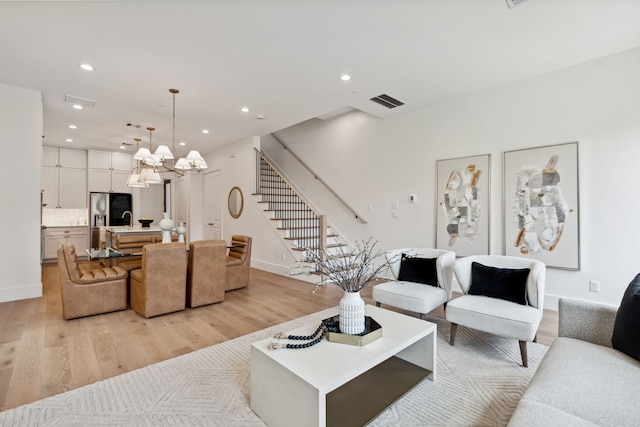living room with stairs, light wood-style floors, a chandelier, recessed lighting, and baseboards