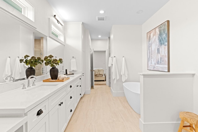 bathroom with a freestanding tub, double vanity, baseboards, and recessed lighting