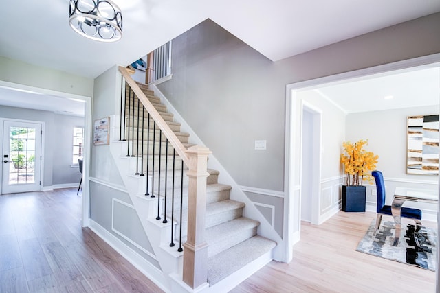 staircase featuring wood finished floors, a chandelier, and baseboards