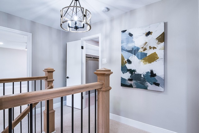 hallway featuring an upstairs landing, baseboards, and a chandelier