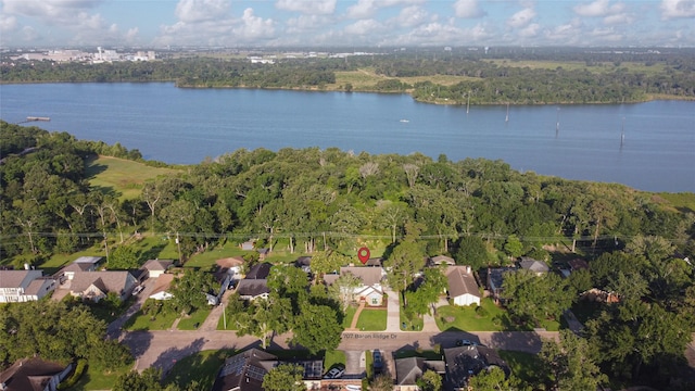 view of property location featuring a forest, a nearby body of water, and nearby suburban area