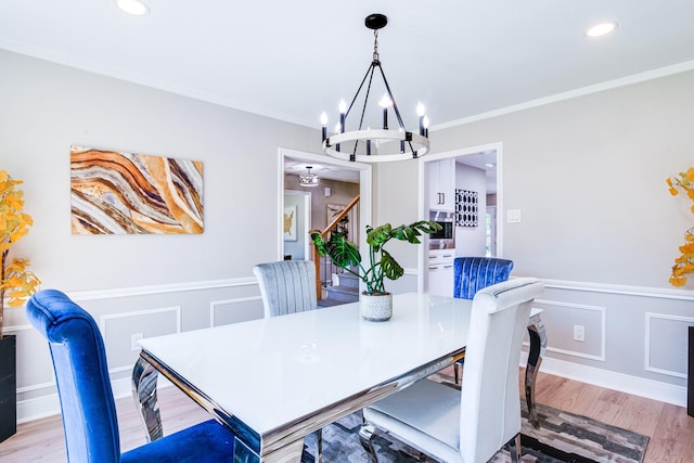 dining room featuring a chandelier, light wood finished floors, ornamental molding, recessed lighting, and stairs