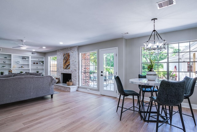 dining area featuring light wood finished floors, a chandelier, a fireplace, recessed lighting, and ceiling fan