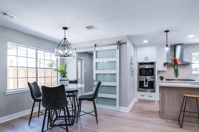 dining area featuring a barn door, baseboards, light wood-style floors, recessed lighting, and a chandelier