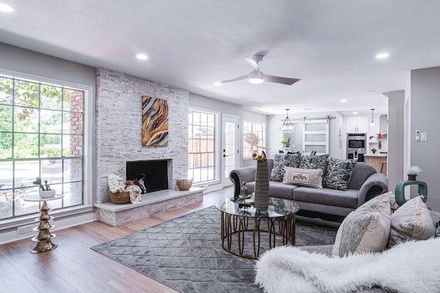 living room featuring plenty of natural light, wood finished floors, ceiling fan, a fireplace, and recessed lighting