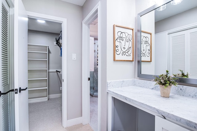 bathroom featuring vanity, baseboards, and a spacious closet