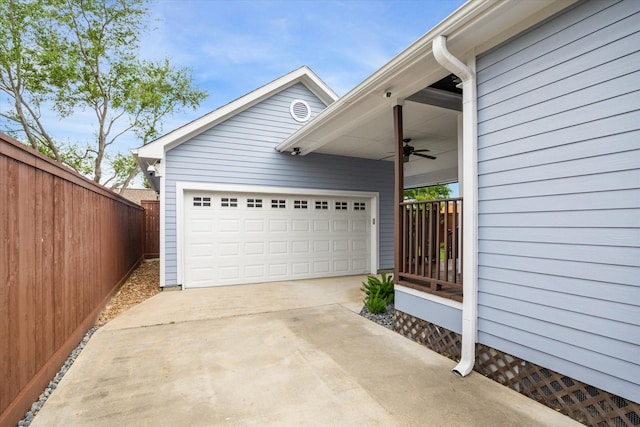 garage featuring fence, concrete driveway, and ceiling fan