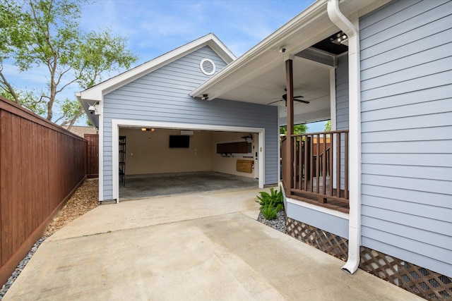 garage with a ceiling fan, fence, and concrete driveway