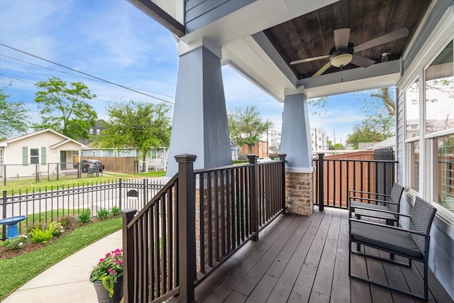 wooden deck with ceiling fan, a porch, fence, and a residential view