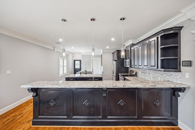 kitchen featuring stainless steel appliances, baseboards, wood finished floors, decorative backsplash, and light stone counters