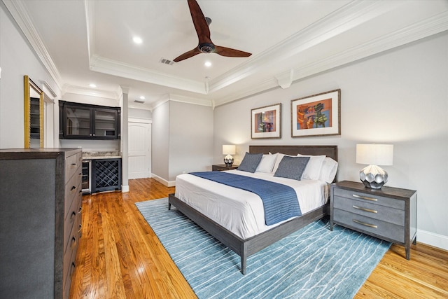 bedroom with a tray ceiling, light wood-style flooring, baseboards, crown molding, and recessed lighting