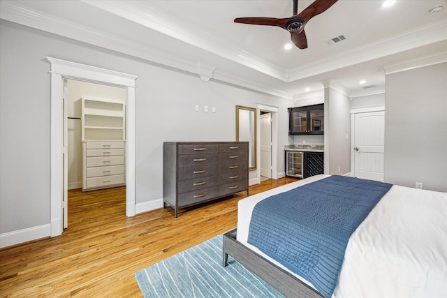 bedroom featuring light wood finished floors, crown molding, recessed lighting, baseboards, and ensuite bathroom