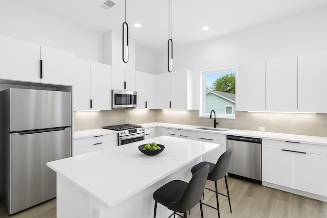 1264 Finnigan St, Houston, TX 77020 - kitchen with stainless steel appliances, a sink, a kitchen island, a kitchen bar, and white cabinets