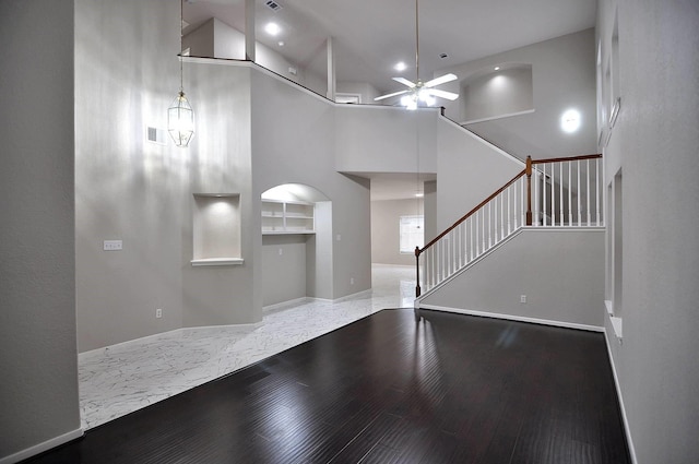 unfurnished living room featuring ceiling fan, baseboards, stairs, a high ceiling, and recessed lighting