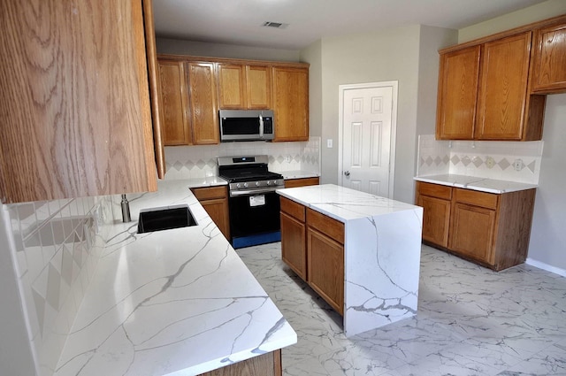 kitchen with appliances with stainless steel finishes, a sink, light stone countertops, decorative backsplash, and brown cabinets