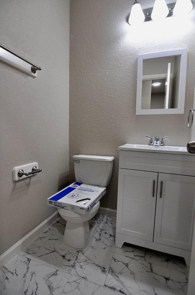 bathroom with toilet, baseboards, vanity, and marble finish flooring