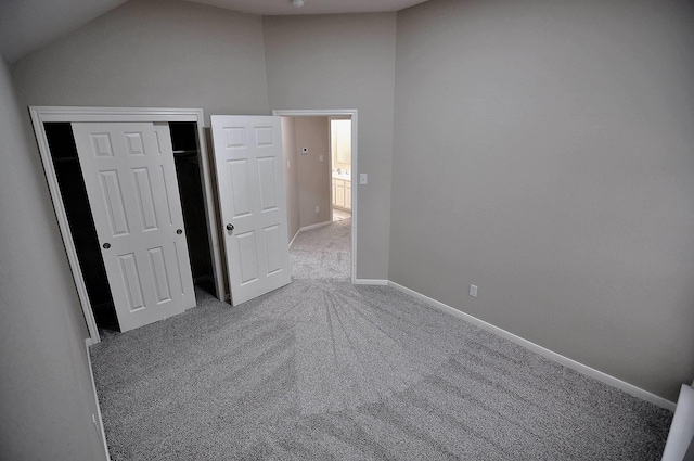 unfurnished bedroom with carpet floors, vaulted ceiling, baseboards, and a closet