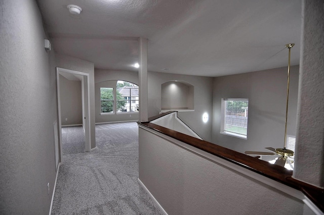 hall featuring carpet, an upstairs landing, and baseboards