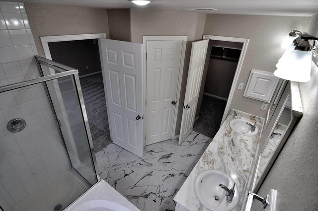 full bath featuring a shower stall, double vanity, a walk in closet, and marble finish flooring