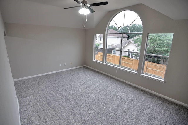 spare room with carpet floors, ceiling fan, vaulted ceiling, and baseboards
