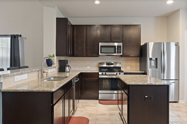 18910 S Sapling Oaks Pl, Magnolia, TX 77355 - kitchen with stainless steel appliances, a sink, a center island, dark brown cabinetry, and tasteful backsplash