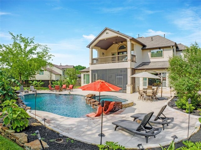 14710 Turquoise Ct, Willis, TX 77378 - rear view of property featuring a balcony, a patio, stucco siding, fence, and a pool with connected hot tub