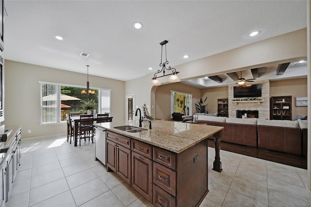 14710 Turquoise Ct, Willis, TX 77378 - kitchen with a sink, light tile patterned flooring, stainless steel dishwasher, a stone fireplace, and recessed lighting