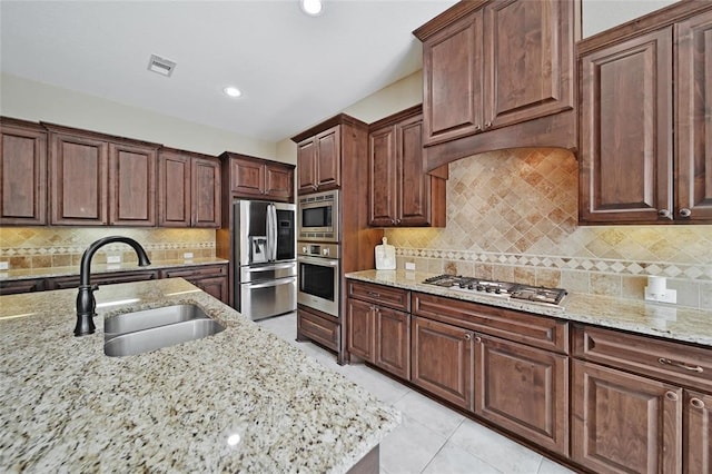 14710 Turquoise Ct, Willis, TX 77378 - kitchen featuring appliances with stainless steel finishes, a sink, light stone countertops, tasteful backsplash, and recessed lighting