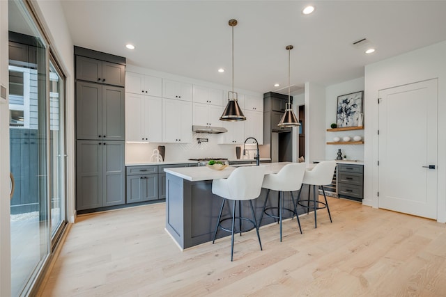 kitchen with gray cabinets, a sink, light wood-type flooring, healthy amount of natural light, and recessed lighting