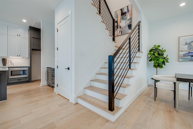 stairs featuring wood finished floors, recessed lighting, wine cooler, and baseboards