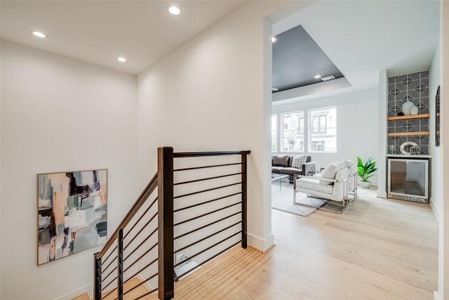 corridor featuring recessed lighting, an upstairs landing, light wood finished floors, baseboards, and beverage cooler
