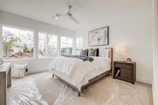 bedroom featuring light colored carpet, baseboards, and a ceiling fan