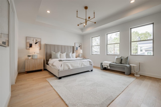 bedroom featuring a tray ceiling, a chandelier, light wood finished floors, recessed lighting, and baseboards