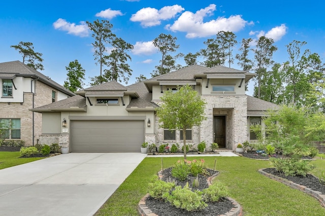 prairie-style house featuring stucco siding, a front yard, roof with shingles, concrete driveway, and stone siding