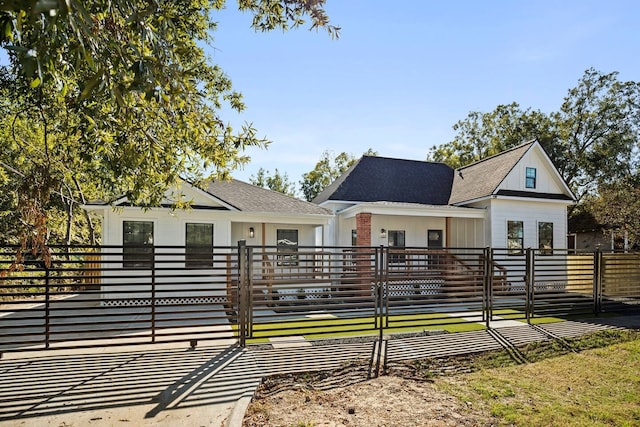 view of front facade with a fenced front yard and a shingled roof