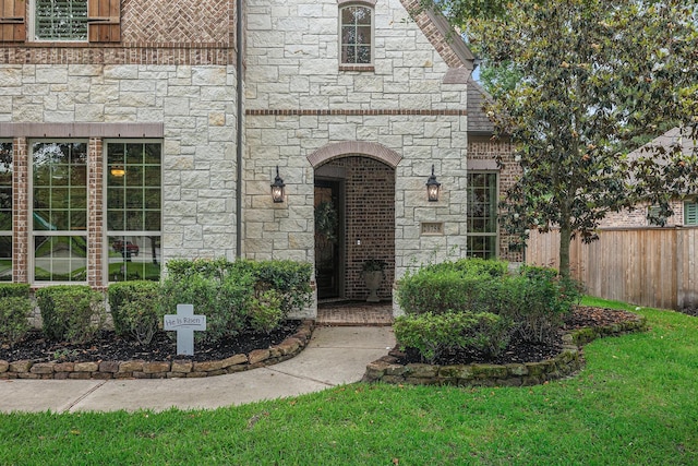 doorway to property with stone siding and fence