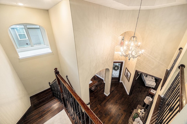 stairway featuring hardwood / wood-style flooring, arched walkways, a chandelier, recessed lighting, and a high ceiling