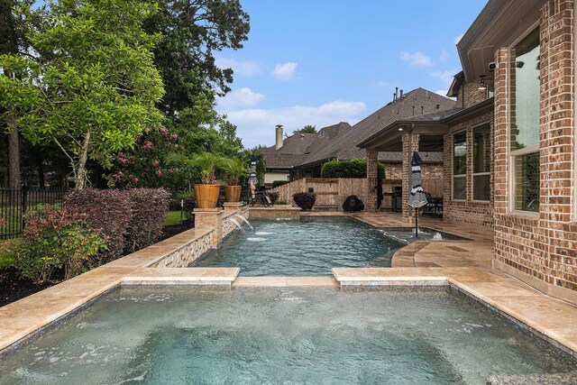 view of pool featuring a fenced backyard, a pool with connected hot tub, and a patio area