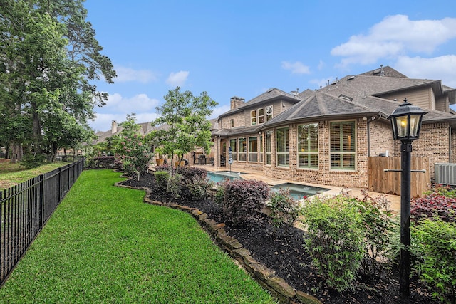 back of house featuring brick siding, a patio area, central AC unit, roof with shingles, and an in-ground hot tub