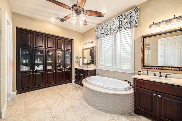 bathroom featuring a bath, ceiling fan, two vanities, and tile patterned floors