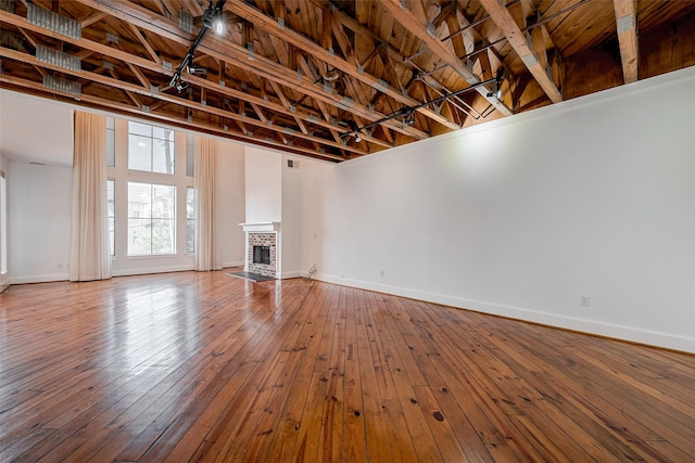 178 Reinicke St, Houston, TX 77007 - unfurnished living room featuring wood-type flooring, baseboards, a brick fireplace, and a towering ceiling
