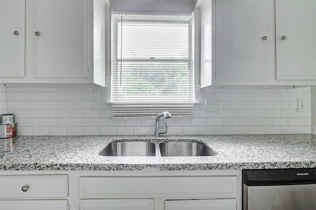 kitchen featuring stainless steel dishwasher, a sink, and white cabinetry