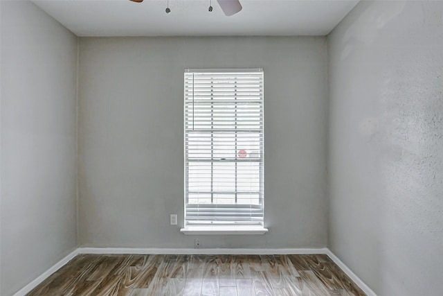 spare room featuring a ceiling fan, wood finished floors, and baseboards
